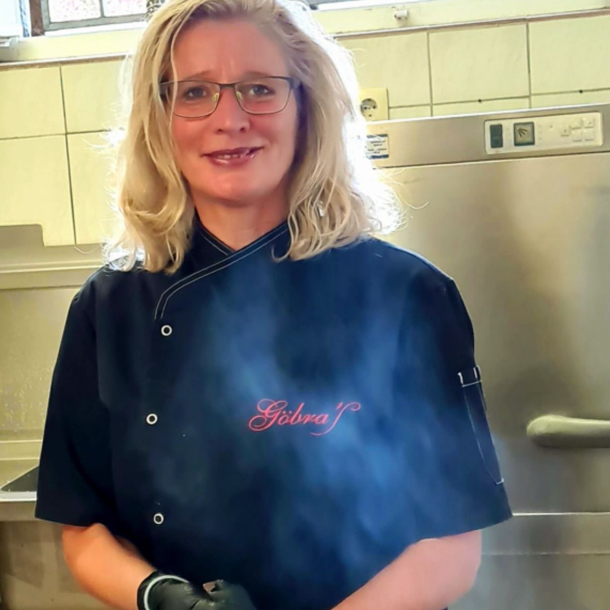 Astrid Schulze in der Küche, in schwarzer Kochjacke mit dem Schriftzug Göbra’S