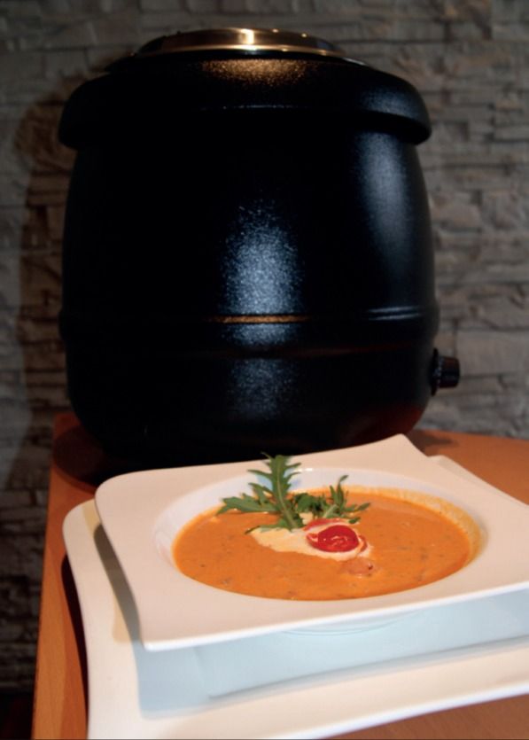 Tomatencremesuppe im Teller vor einem Suppentopf