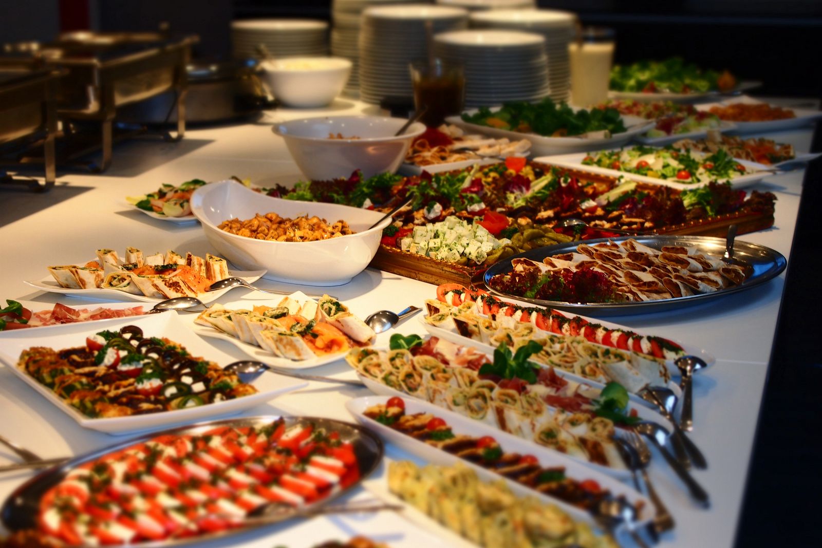 Buffetreihe mit Caprese, Wraps und Antipasti, im Hintergrund Chafing Dishes