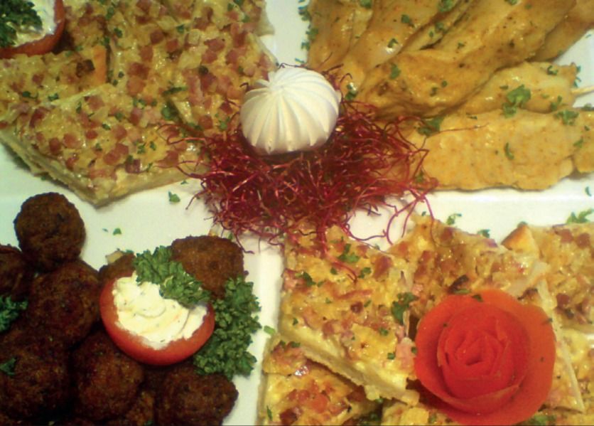 Platte mit Quiche-Stücken, frittierten Bällchen, gefüllter Kirschtomate und Tomatenrose
