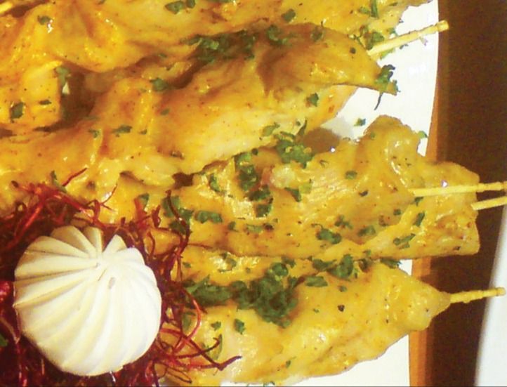Hähnchenspieße mit Kräutern, daneben ein Sahnetupfen