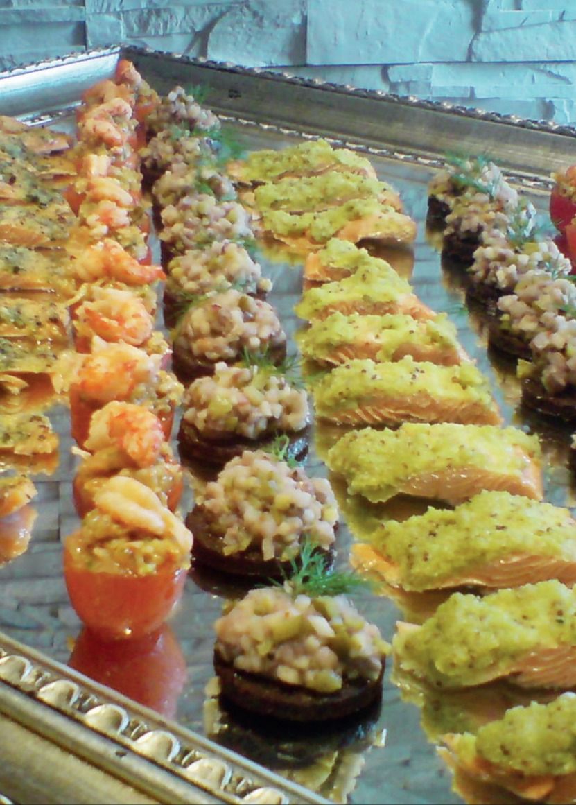 Silbertablett mit Reihen belegter Kanapees und gefüllter Häppchen